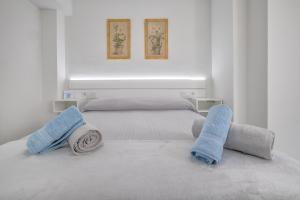 a white bedroom with two beds with towels on them at Apartamentos Haranas, parking incluido in Córdoba