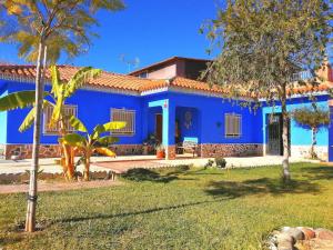 una casa azul con árboles delante de ella en La Morada del Yayo 15 minutos de Sevilla, en Las Pajanosas