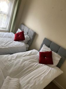 two beds with red pillows on them in a bedroom at Elite Wolverhampton short/long stays in Wolverhampton