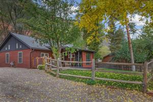 a red cabin with a fence in front of it at Cozy Modern House seconds from Roaring Fork River in Glenwood Springs