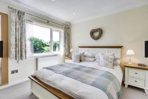 a white bedroom with a bed and a window at Roxby, Pooley Bridge in Pooley Bridge