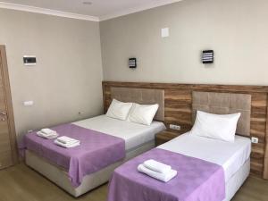 two beds in a room with purple sheets at Can Butik Otel in Ardeşen