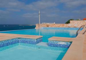 ein großer Pool mit blauem Wasser und dem Meer in der Unterkunft Villa Atum. Stella Maris Exclusive in Vila do Maio