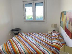 een slaapkamer met een kleurrijk bed en een raam bij Moderna y alegre vivienda junto al mar . in Roquetas de Mar