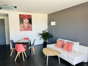 a living room with a white couch and a table at T2 Front de Mer 2pers 1 minute de la plageT2 de 44 m2 plus terrasse 16m2 , vue mer panoramique et en face de la plage Cet appartement refait à neuf bénéficie d'un confort et d un équipement optima Cet appartement est idéal pour 2 personnes avec sa chamb in Le Lavandou