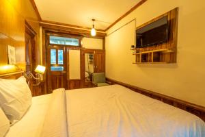 a bedroom with a bed and a flat screen tv at Holiday Home International in Manāli