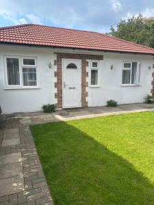 a white house with a red roof and a yard at Dannifar Guest House in London