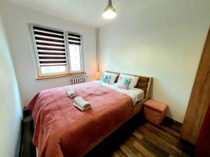 um quarto com uma cama com um cobertor vermelho e uma janela em Happy Stay em Gliwice