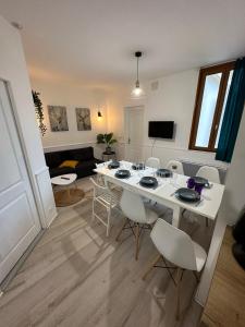 sala de estar con mesa blanca y sillas en Appartement spacieux - proche centre et therme en Bagnères-de-Bigorre