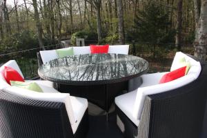 a patio with a glass table and chairs at White Lodge B&B in Cooksbridge