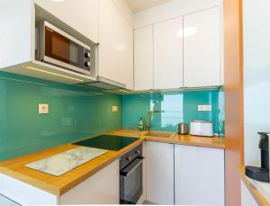 una cocina con armarios blancos y paredes verdes en Sunset Resort 507, en Fonyód