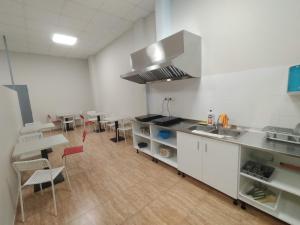 cocina con armarios blancos, mesa y sillas en Albergue Cotón en Negreira
