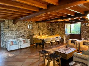 Una habitación con una mesa y sillas y una pared de piedra. en Casa Rural O Vilar, en Mera de arriba