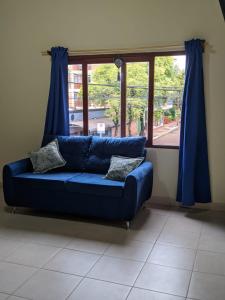 - un canapé bleu dans une chambre avec fenêtre dans l'établissement Colibri Apart Eldorado, à Eldorado