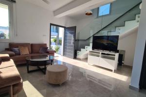 a living room with a couch and a tv at Protaras LUX Villa, Swimming pool, BBQ grill, Near beach in Protaras