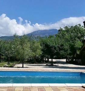 a blue swimming pool with trees and mountains in the background at Villa Segreta, Mount Etna in Belpasso