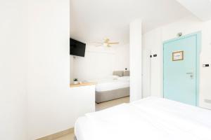 a white bedroom with a bed and a tv at Hotel San Carlo in Lugano