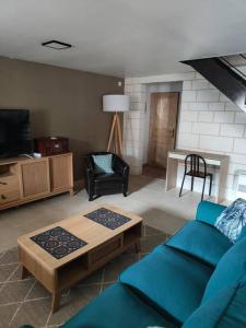 ein Wohnzimmer mit einem blauen Sofa und einem TV in der Unterkunft Gîte Les Rouffy in Saint-Mard-lès-Rouffy