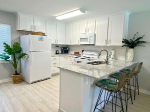 uma cozinha com armários brancos e um frigorífico branco em Sand Dollar 2 by ALBVR - Walking distance to Hangout! Beautifully redone condo! em Gulf Shores