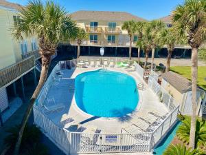 uma vista sobre uma piscina com cadeiras e palmeiras em Sand Dollar 2 by ALBVR - Walking distance to Hangout! Beautifully redone condo! em Gulf Shores