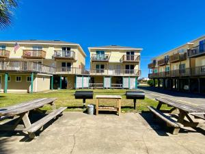 a group of picnic tables in front of a building at Sand Dollar 2 by ALBVR - Walking distance to Hangout! Beautifully redone condo! in Gulf Shores