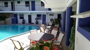 un patio con mesa y sillas junto a una piscina en Hotel Ponta do Morro, en Tiradentes