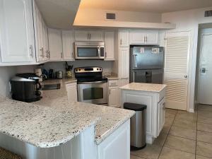 een keuken met witte kasten en granieten aanrechtbladen bij Summer House 703B by ALBVR - Great Beachfront Condo with Oversized Balcony & Amazing Views! in Orange Beach