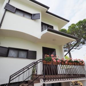 een wit huis met een balkon met bloemen erop bij villetta con piscina a due passi dal mare in Duna Verde