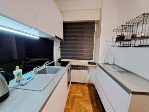 a white kitchen with a sink and a window at Friday Apartments in Zagreb