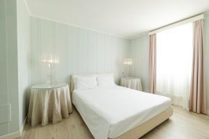 a white bedroom with a large bed and a window at Hotel Eden in Sistiana
