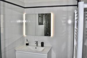 La salle de bains blanche est pourvue d'un lavabo et d'un miroir. dans l'établissement Sublime Studio Festival Cannes, à Cannes