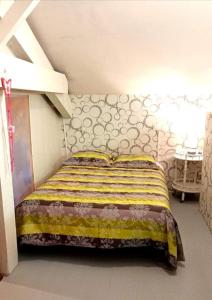 - une chambre dotée d'un lit avec une couverture jaune et blanche dans l'établissement le Refuge d'Eugénie, à Bahus-Soubiran