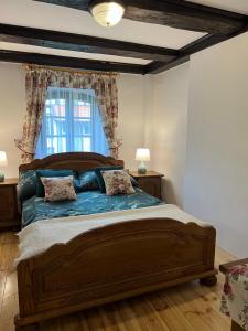 sypialnia z dużym drewnianym łóżkiem z 2 poduszkami w obiekcie Apartament w XIX-wiecznym Spichlerzu nad Jeziorem z dostępem do parku i widokiem na Dworek Modrzewiowy z 1823 roku w mieście Szteklin