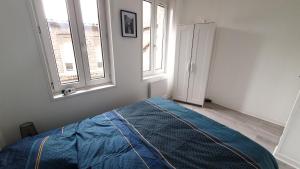 una camera con un letto blu e due finestre di Charmant deux pièces centre Cantimpré3 a Cambrai