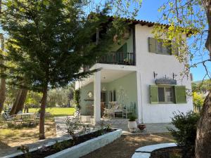 ブアブロウにあるLa maison des vacancesの緑のシャッターとパティオ付きの白い家