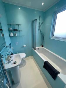 La salle de bains est pourvue de murs bleus, d'un lavabo et d'une baignoire. dans l'établissement Rivendell Room Only Studios, à Swanage