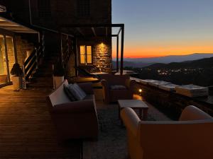 a patio with couches and tables and a sunset at Mikro Papigo 1700 Hotel & Spa in Papingo