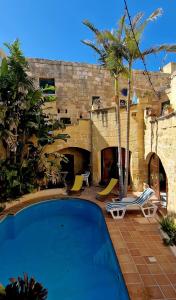 un complejo con piscina y palmeras en Haven Farmhouse B&B, en Għarb