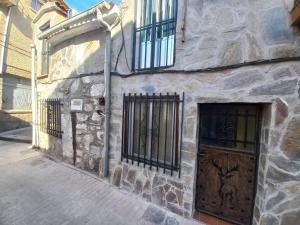un edificio de piedra con dos puertas y puertas de hierro forjado en El Laberinto, en Sotillo de la Adrada