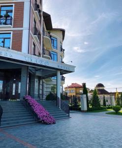 un edificio con escaleras y flores púrpuras delante en Shato Hotel ШАТО, en Chervonograd
