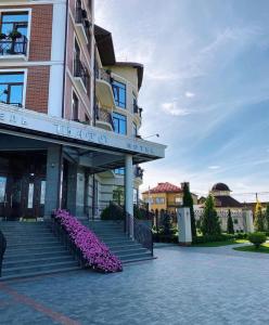 ein Gebäude mit Treppen und lila Blumen davor in der Unterkunft Shato Hotel in Chervonograd