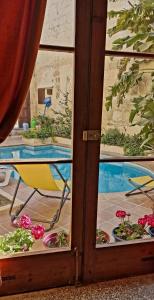 una puerta corredera de cristal con una silla y flores al aire libre en Haven Farmhouse B&B, en Għarb