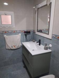 y baño con lavabo, espejo y aseo. en La casita de colores en Elche