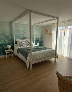 una camera da letto con un letto a baldacchino in una stanza di La Maison Tchanquée jusqu'à 12 personnes Jacuzzi privé a Gujan-Mestras