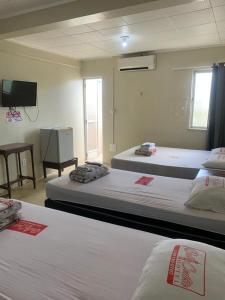 a room with two beds and a flat screen tv at Hotel BELCENTRO in Belém