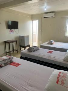 a room with two beds and a flat screen tv at Hotel BELCENTRO in Belém