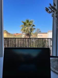 un ordenador portátil sentado en una mesa frente a una ventana en Beautiful Apartment 200m from Beach en Canet-en-Roussillon