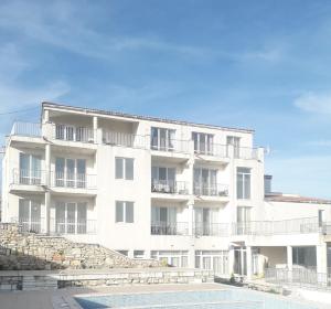 a white apartment building with stairs in front of it at Апартамент с изглед към морето и външен басейн in Balchik