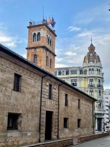 a brick building with a clock tower in a city at Apartamento Jardín de San Feliz / Fontán in Oviedo