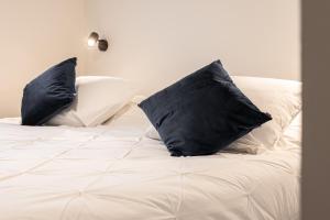 a white bed with two black pillows on it at Villa Zomerrust in De Panne
